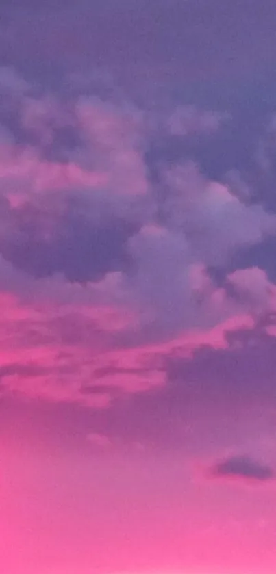 Vibrant pink sky with clouds during sunset, perfect for mobile wallpaper.