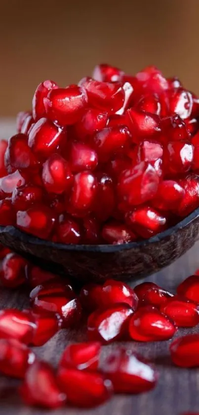 Pomegranate seeds in a rustic wooden bowl on a table.