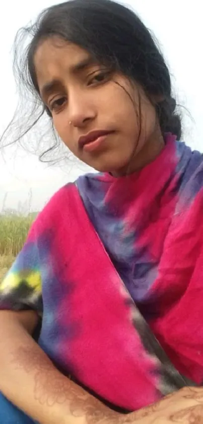 Woman in colorful shawl sitting outdoors.