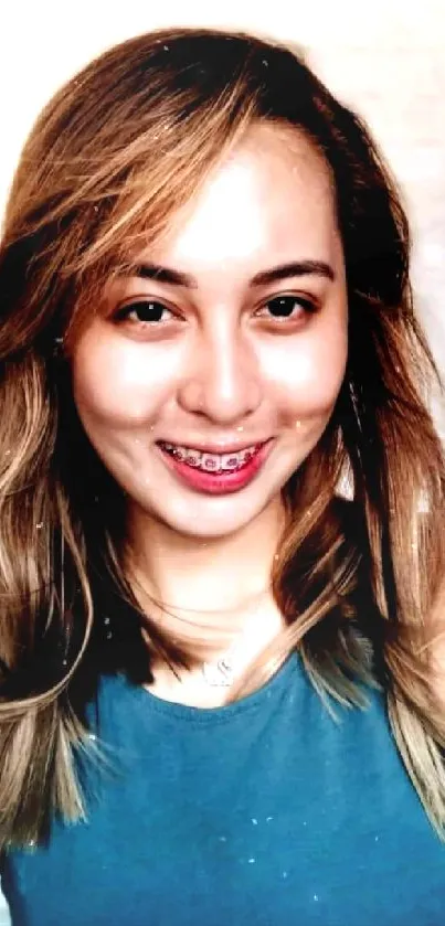 Smiling woman in blue top against a soft background.