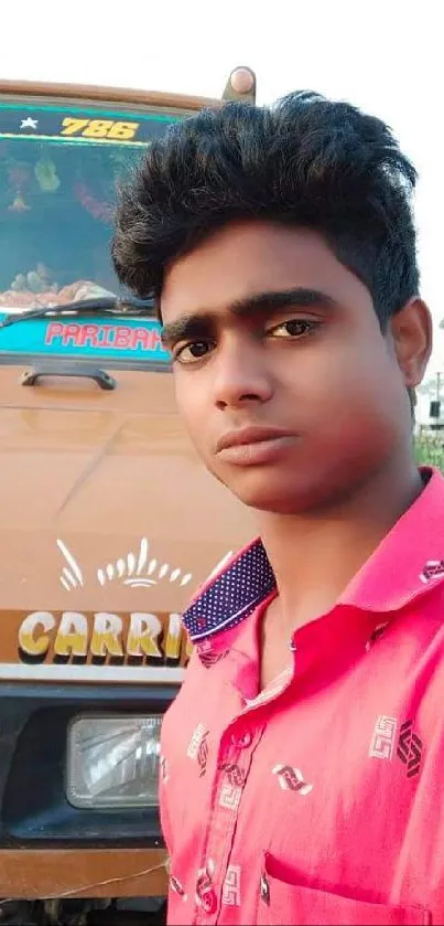 Portrait of a young man in pink shirt with truck backdrop.