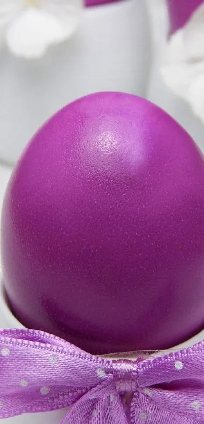 Purple Easter egg with ribbon and white flowers in background.