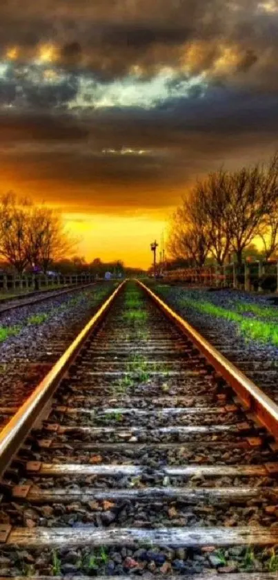 Railway tracks with a vibrant orange sunset and cloudy sky.