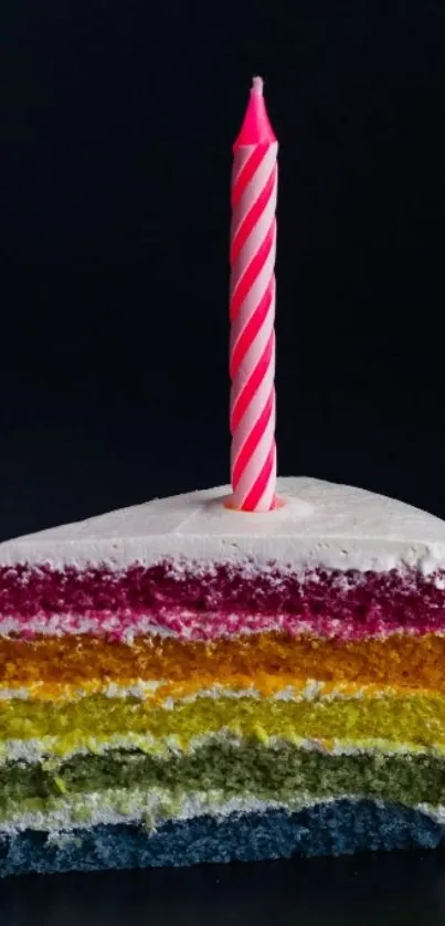 Vibrant slice of rainbow cake with pink candle on black background.