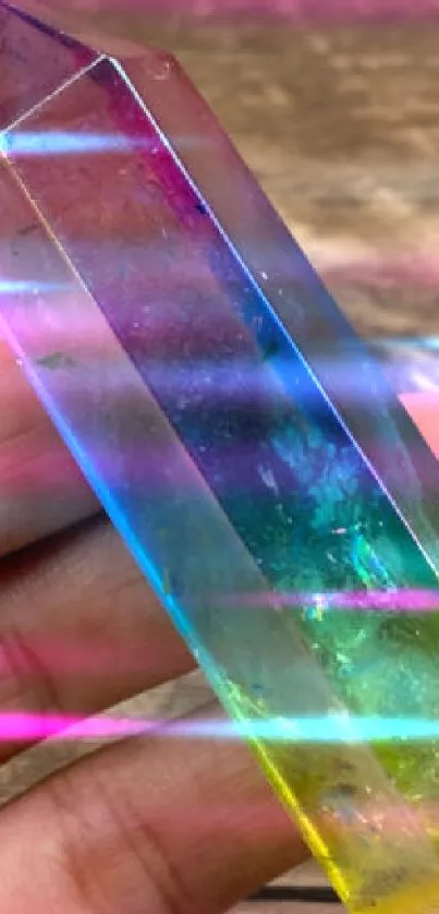 Vibrant rainbow crystal held in hand on wooden background.