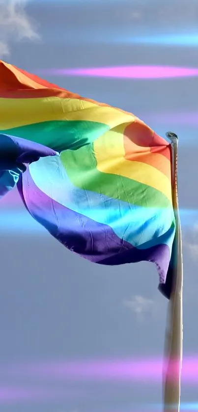 Rainbow flag waves against a bright blue sky wallpaper.