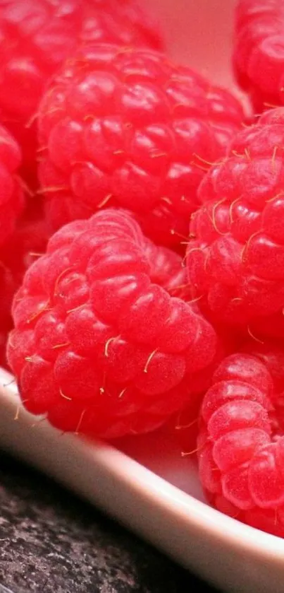 Close-up of red raspberries on a white plate for mobile wallpaper.