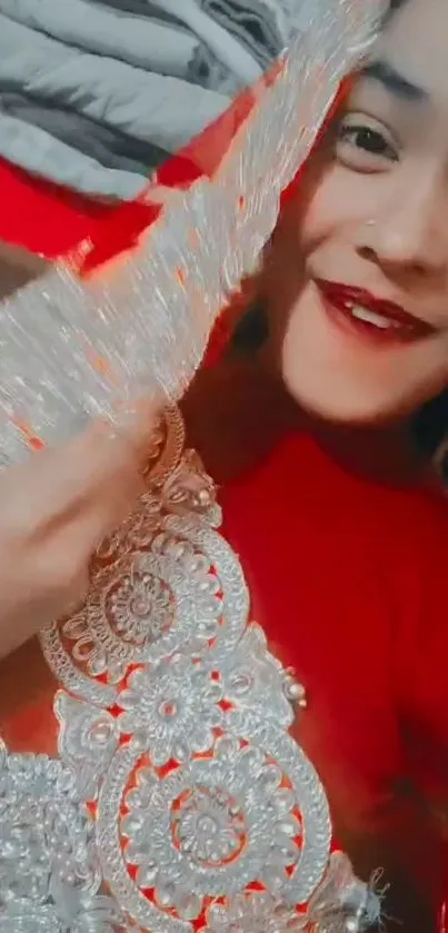 Woman smiling in a red dress with intricate silver embroidery.