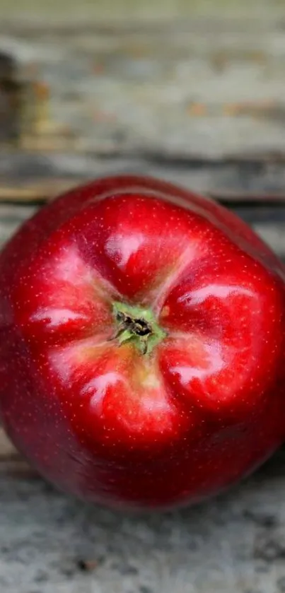 Vibrant red apple on rustic wooden surface wallpaper image.