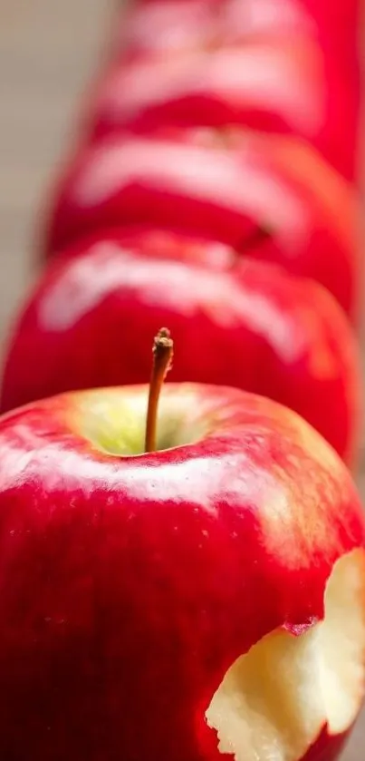 Lineup of vibrant red apples with a bitten apple in focus.