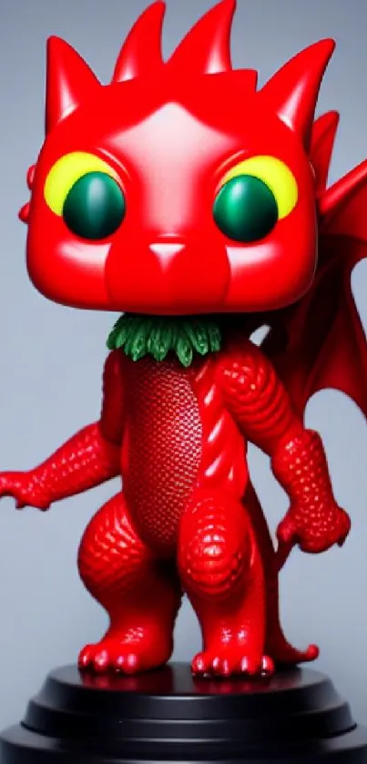 Red dragon toy with green eyes on a dark base and blue background.