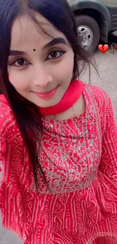 Person in a vibrant red traditional dress, smiling outdoors.