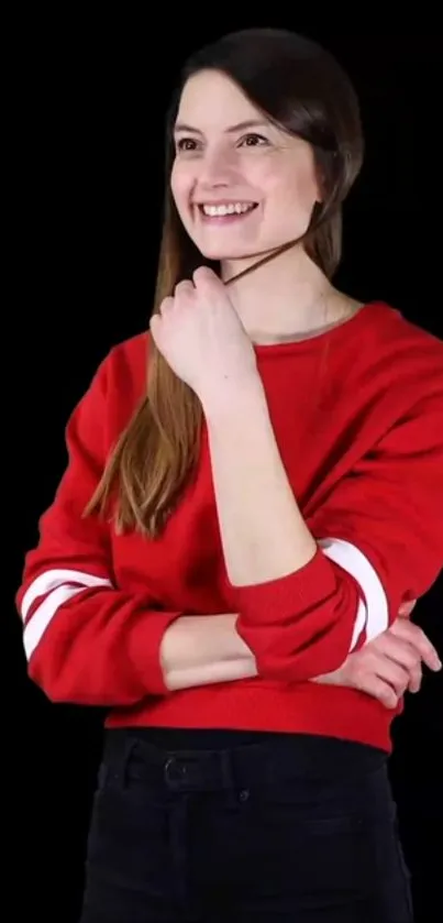 Woman in red sweater on black background, smiling.