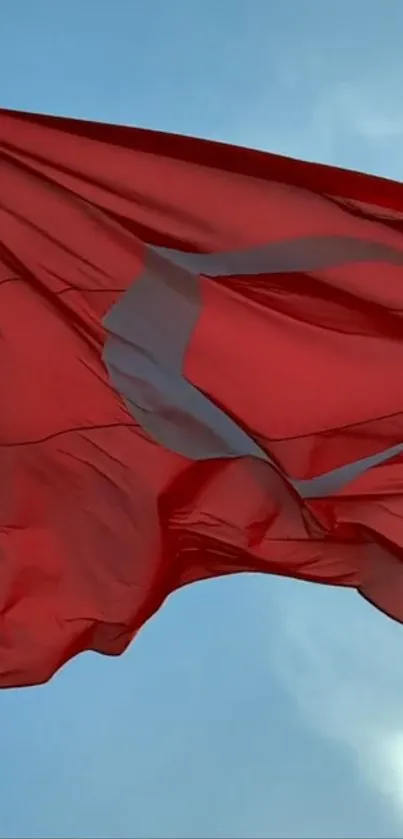 Red flag waving against a bright blue sky.