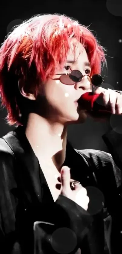 Red-haired performer in black attire with sunglasses, holding a red microphone.