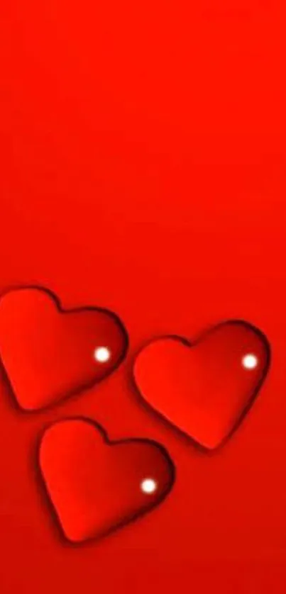 Red wallpaper with three glossy hearts on it.