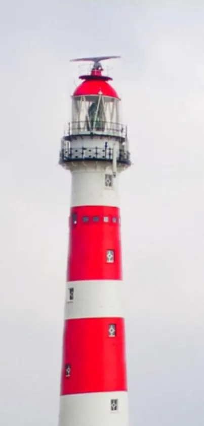 Red and white lighthouse against a cloudy sky.