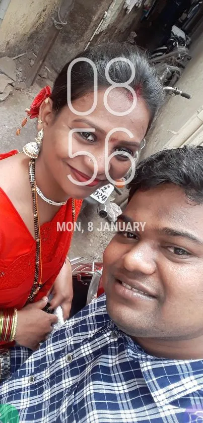 Couple selfie with red saree and vibrant background.