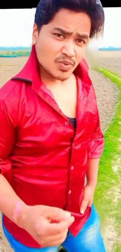 Man in a red shirt standing in a scenic countryside field.