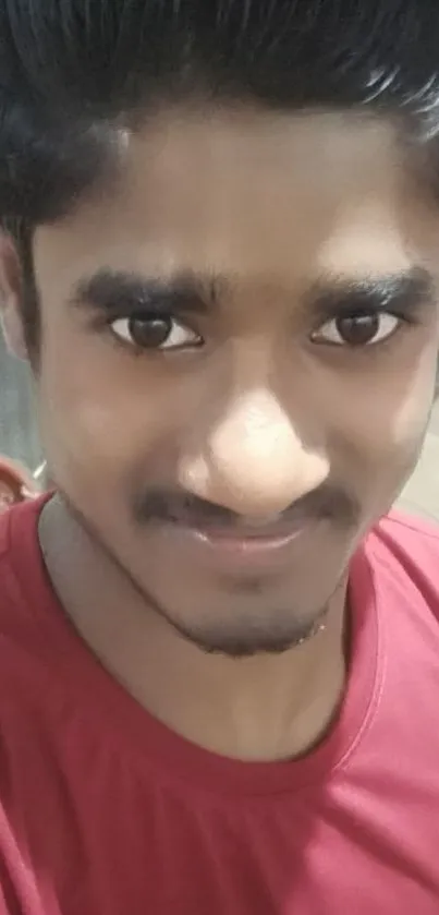 Portrait of a person in a red shirt smiling warmly at the camera.