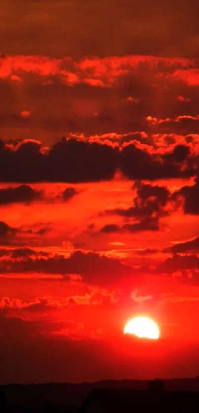 Vibrant red sunset with clouds and glowing horizon on a phone wallpaper.