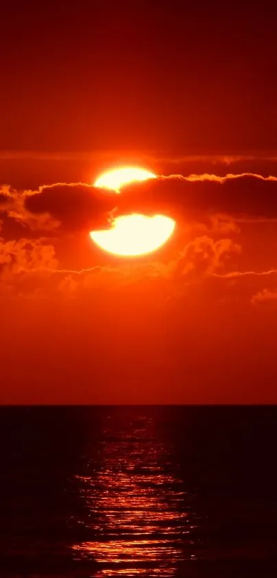 A vibrant red sunset over the ocean, casting a serene glow on the water.