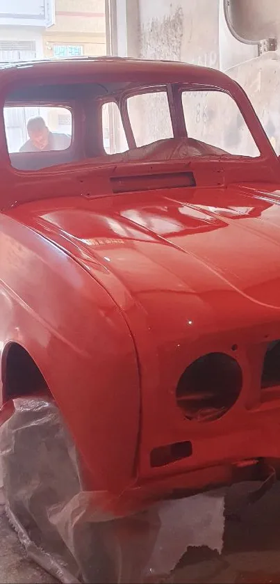 Vibrant red vintage car in garage setting.