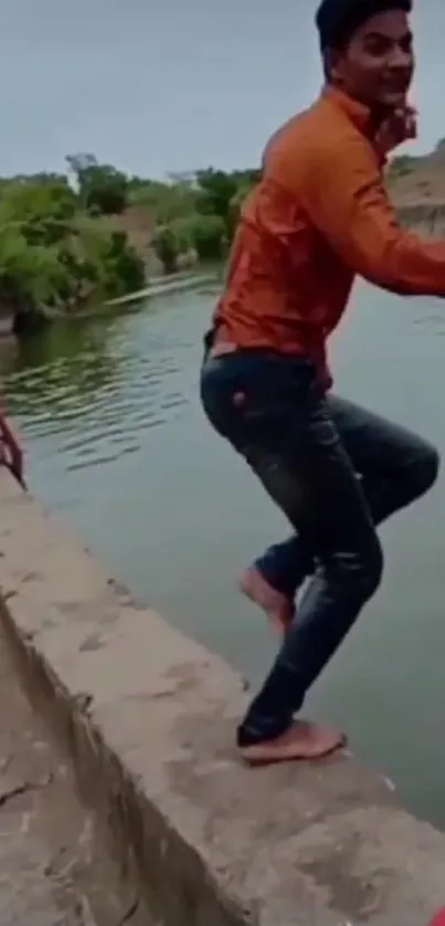 Young man prepares to jump by a riverside, exuding adventure and excitement.