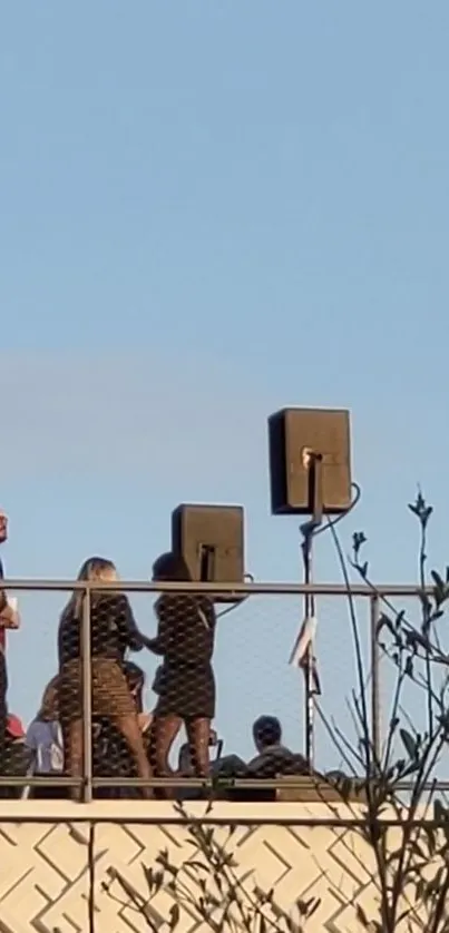 Rooftop gathering with clear blue sky background and industrial railing.