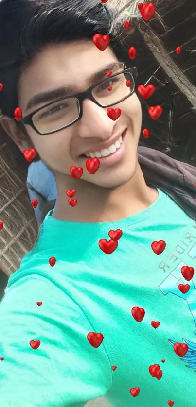 Young person taking a selfie with a rustic background, wearing a teal shirt.