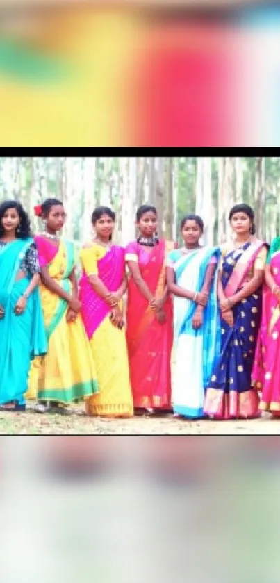 Women in colorful saris stand in a forest.