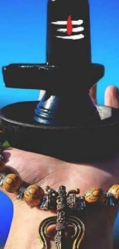 Hand holding a Shivling with beads on a vivid blue background.