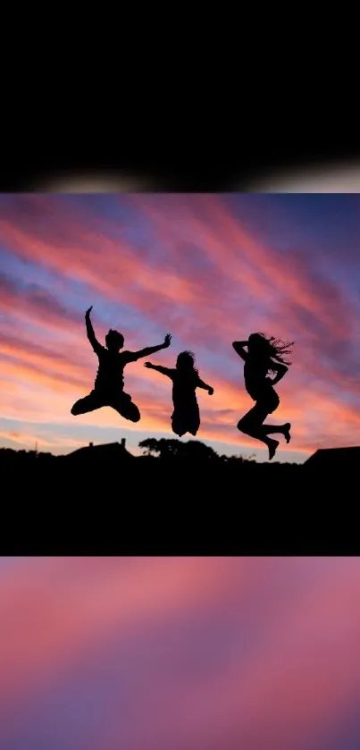 Silhouetted figures jumping against a vibrant sunset sky with colorful clouds.