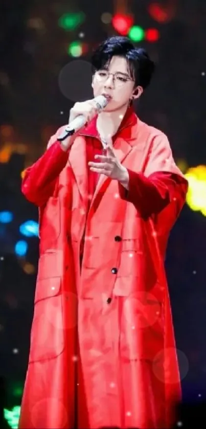 Singer in a red coat performing on a vibrant stage with colorful lights.