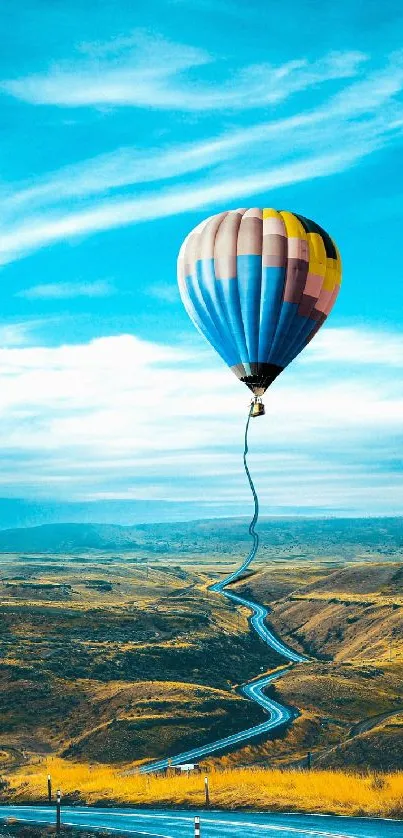 Hot air balloon soaring above a winding road with a vivid blue sky.