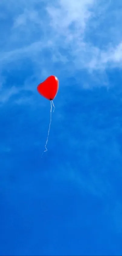 Red heart balloon floating in a vibrant blue sky.