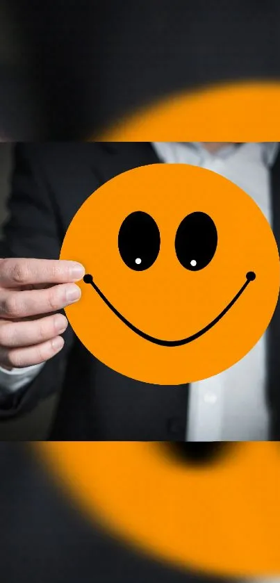 An orange smiley face held by a person in a suit.