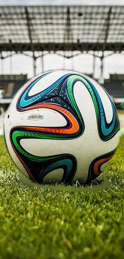 Soccer ball on green field with stadium in background.