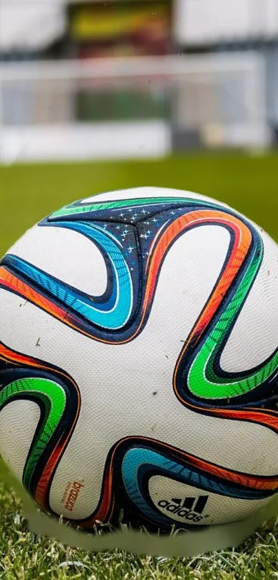 Vibrant soccer ball on green field with stadium backdrop.