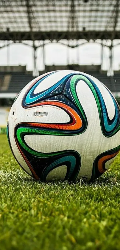 Colorful soccer ball on a green field in a stadium.