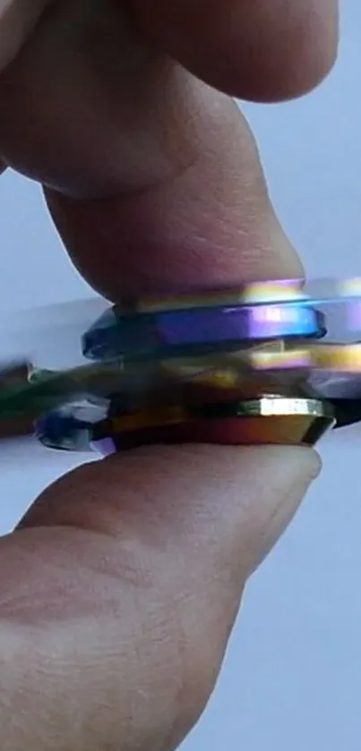 Holographic fidget spinner in motion held between fingers.