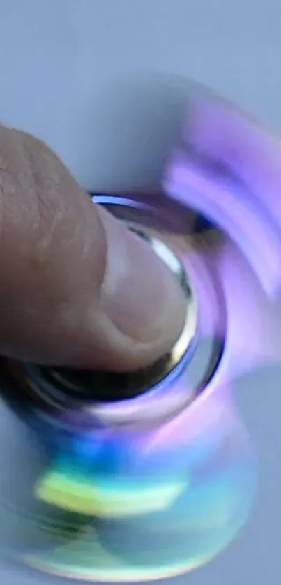 Purple and blue fidget spinner in motion against a blurred background.