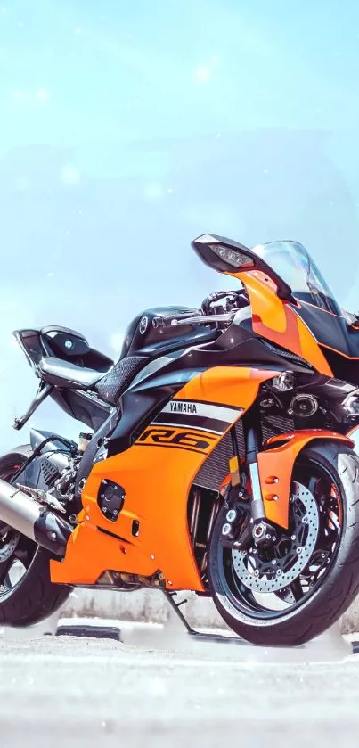 Orange and black sports motorcycle standing with a clear sky background.