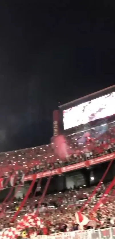 Vibrant red stadium filled with cheering fans at night.