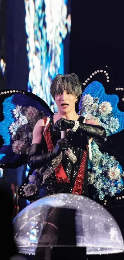 Performer in vibrant butterfly costume with floral accents on stage.