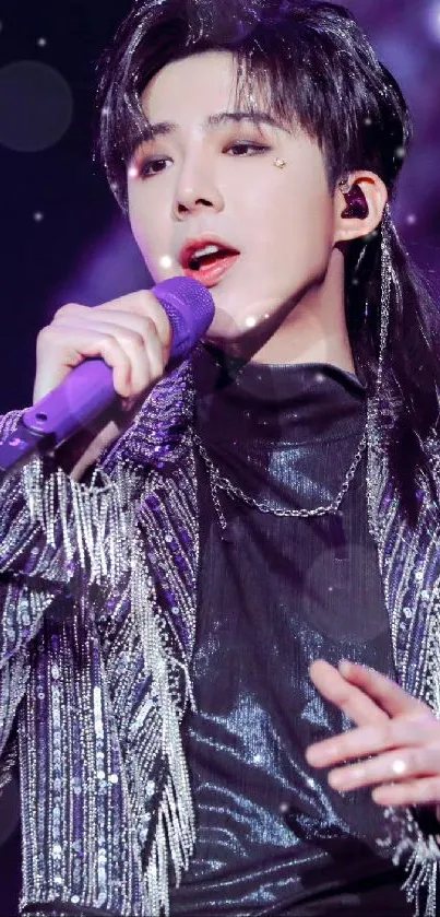 Singer in a stylish outfit on stage with a purple background.