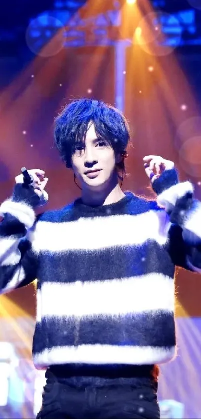 Energetic stage performer in striped outfit under vivid blue lights.