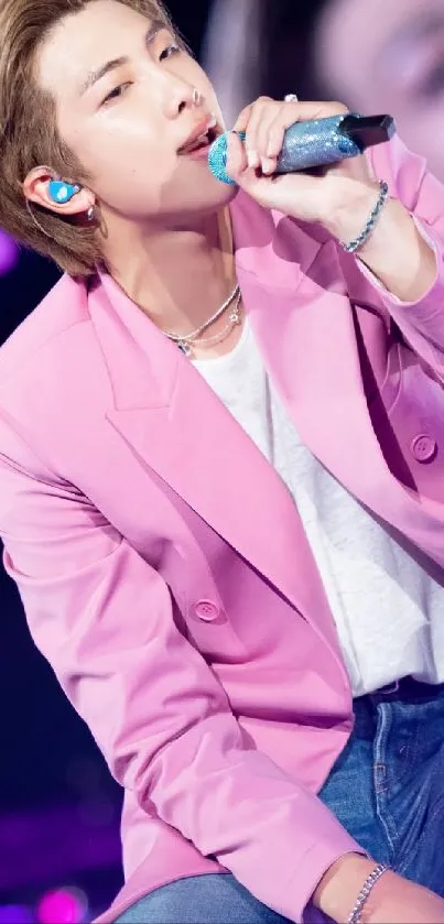 Energetic stage performer in pink jacket holding a glittery microphone.