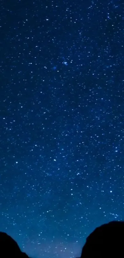 Blue starry night sky with twinkling stars and dark silhouette.