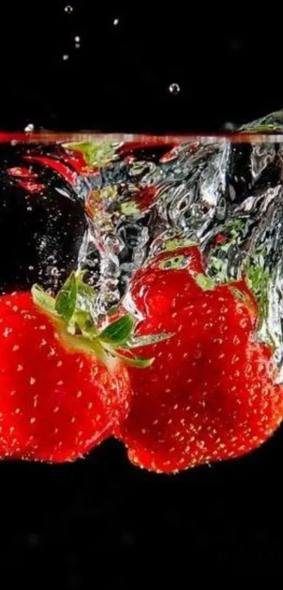 Two vibrant strawberries splash into clear water on a black background.